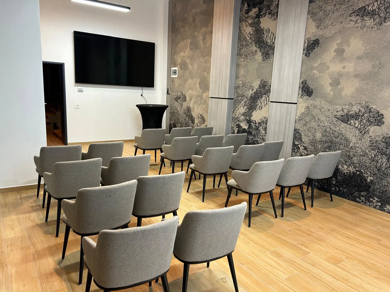 La sala conferenze dell’Aris allestita a platea, con lo schermo e la parete decorata con un bosco