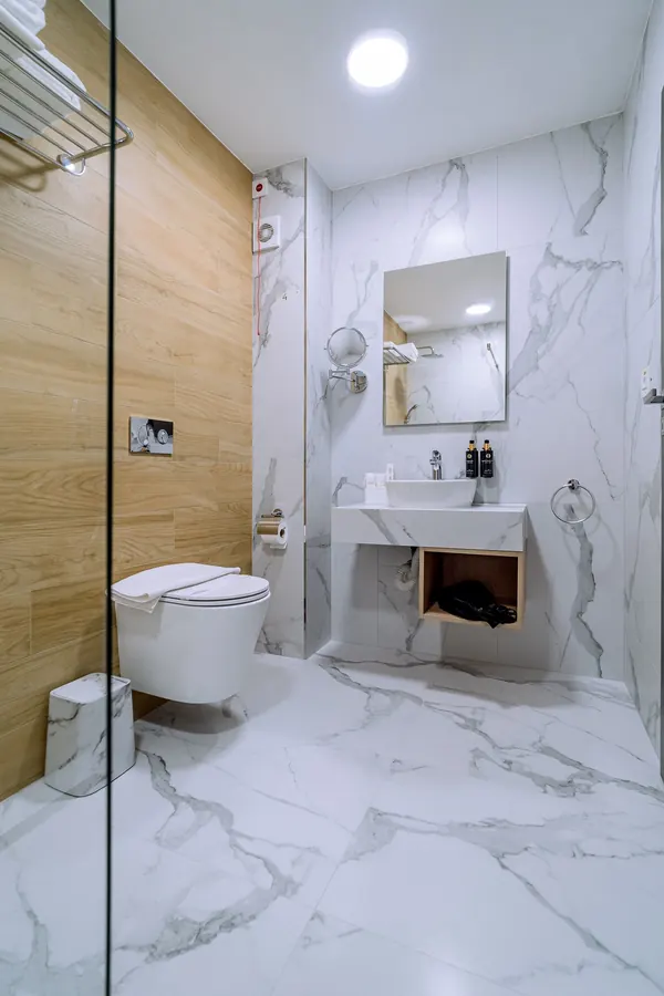 Baño luminoso de mármol blanco y madera