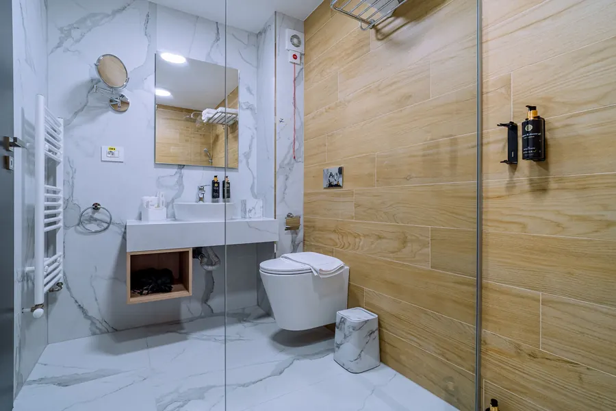 Baño de mármol blanco y madera, con ducha a ras de suelo