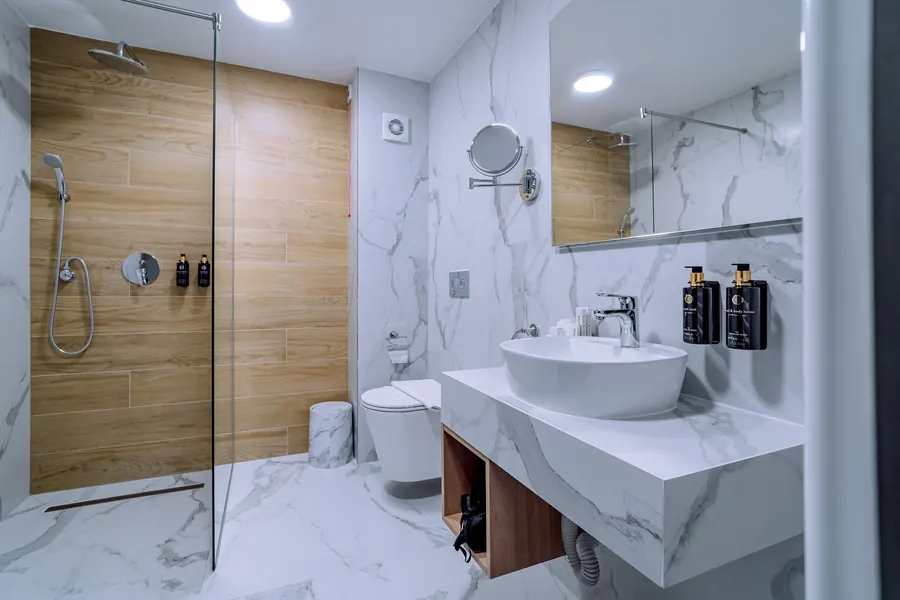 Baño con lavabo sobre encimera de mármol y ducha a ras de suelo