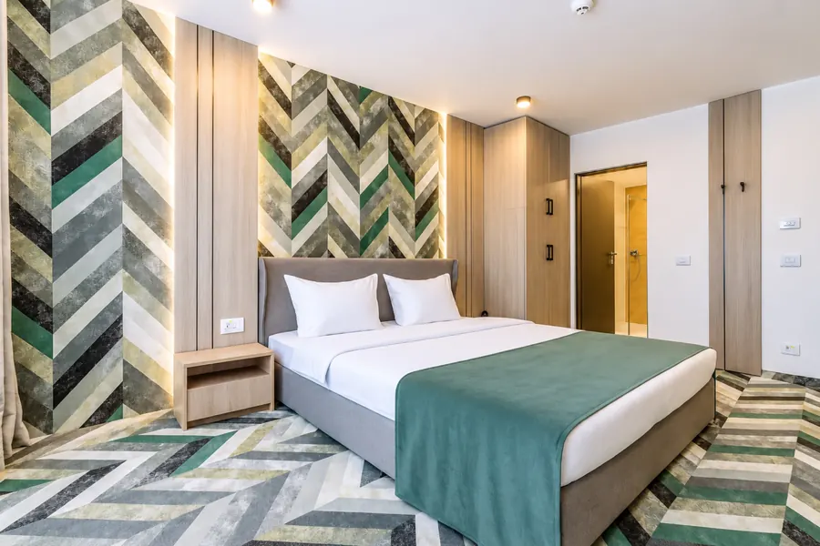 Cama de matrimonio junto a la pared de espiga verde