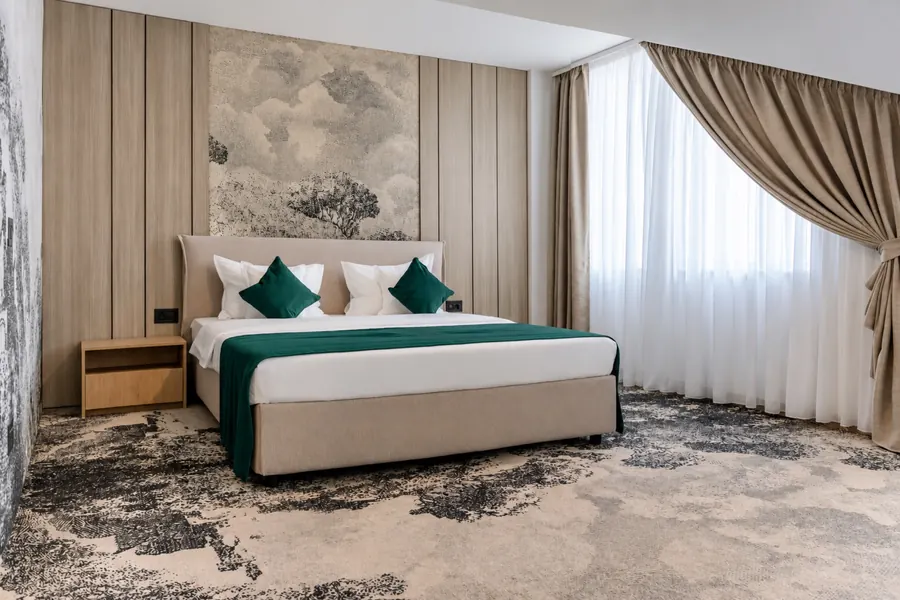 Dormitorio luminoso, con cortinas beige y un paisaje en tonos grises