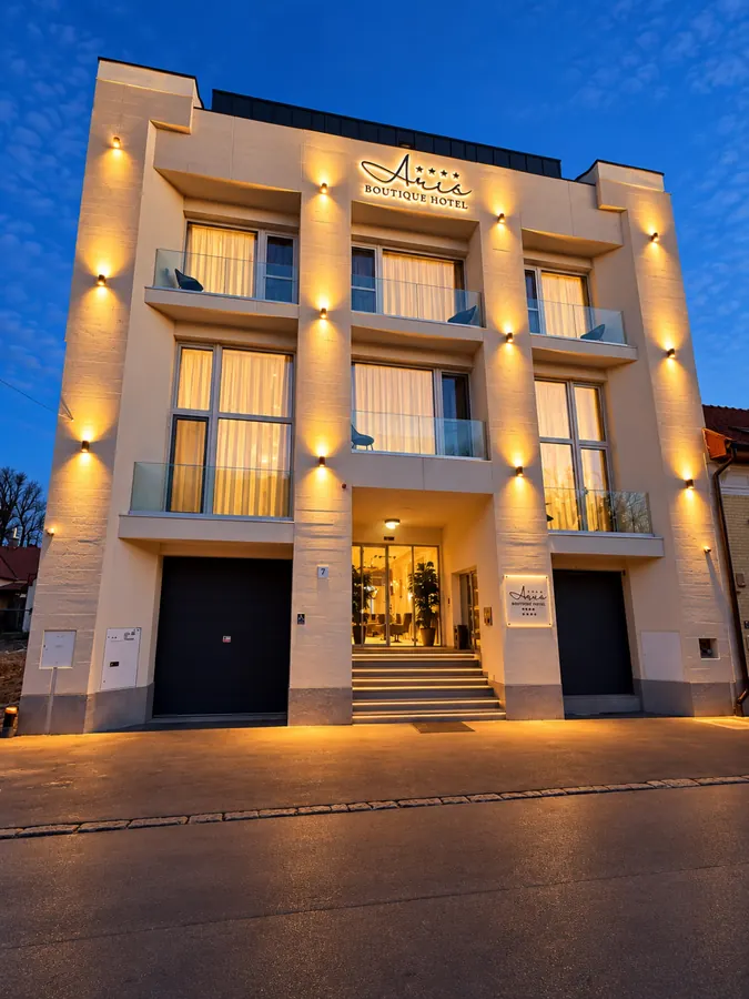 La fachada del hotel Aris al anochecer, con una cálida iluminación arquitectónica