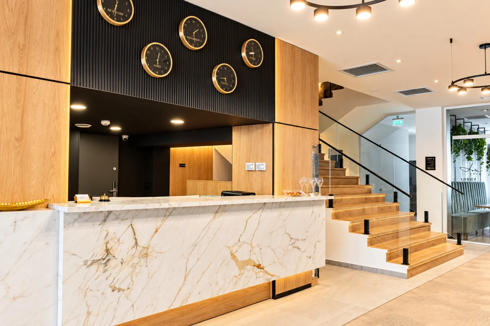 La reception dell’hotel, con bancone in marmo e orologi alla parete