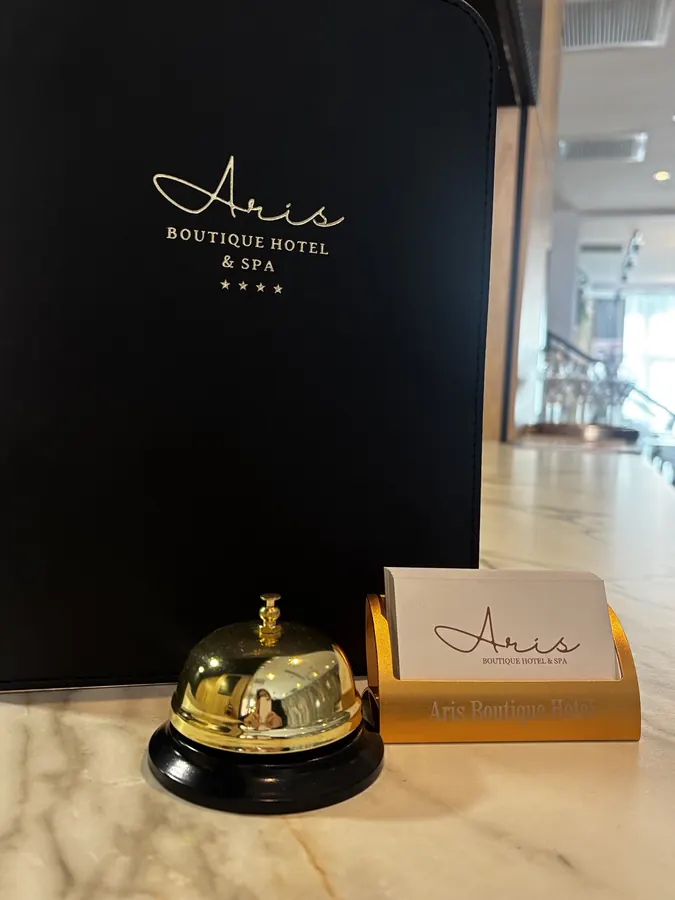 Campanilla dorada y tarjetas de visita de Aris en recepción