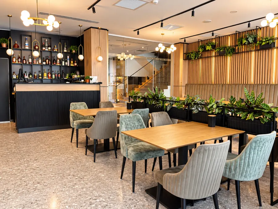 El lobby bar, con mesas de madera y plantas