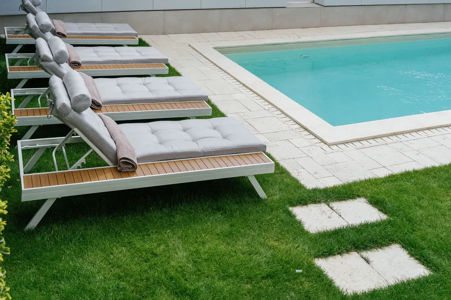 Weiße Sonnenliegen mit Auflagen am Hotelpool