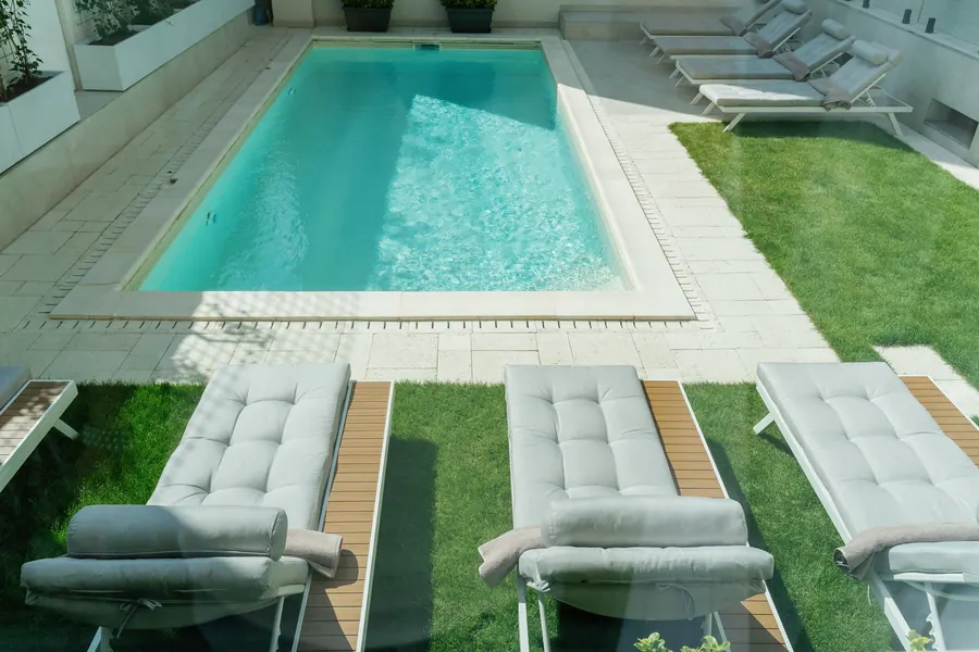 Der Pool von oben, mit Sonnenliegen auf dem Rasen
